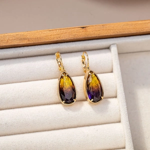 Dettaglio degli orecchini a goccia con pietre sfumate giallo e viola in montatura d'oro