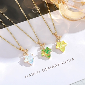 Detail of three maple leaf necklaces with opal textures and gold chains on white paper