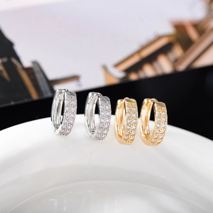 Détail de boucles d'oreilles huggie or et argent avec pavage de zircons à trois rangs