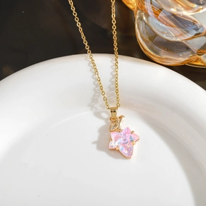 Detail of pink maple leaf crystal pendant on a gold necklace over a ceramic plate