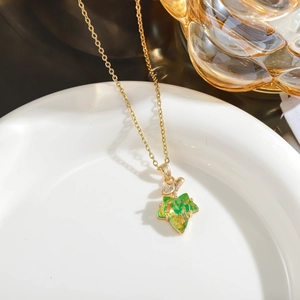 Detailed macro view of the translucent green maple leaf pendant on a gold chain necklace