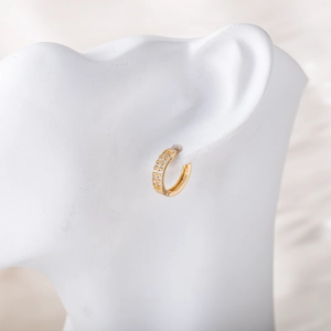 Gros plan de créoles dorées avec double rangée de zircons sur un mannequin blanc