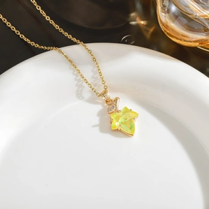 Close-up of golden maple leaf pendant with iridescent green stone and tiny white zircons
