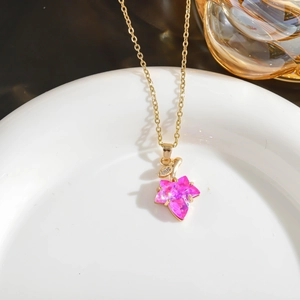 Detail of maple leaf pendant necklace featuring pink crystal and golden micro-pave diamonds