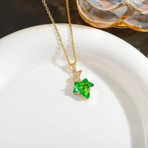 Detailed close-up of green crystal maple leaf pendant on a fine gold-plated chain