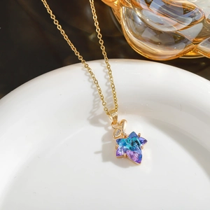 Detail of star pendant necklace with gradient crystal and gold chain on white ceramic