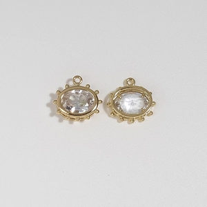 Detail of gold oval Evil Eye charms with faceted clear crystals and beaded metal edges