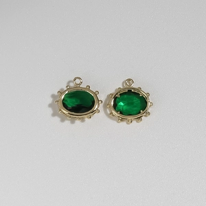 Detailed macro view of two oval gold stainless steel evil eye pendants with green stones