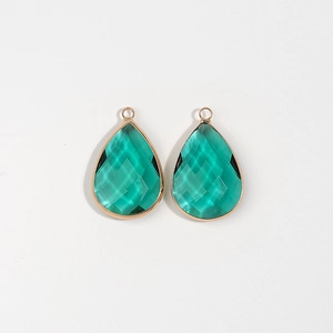 Detailed macro view of teardrop emerald faceted gemstones with gold plated bezel frame