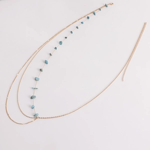 Détail de la chaîne de taille dorée à plusieurs rangs avec pierres turquoise et fermoir