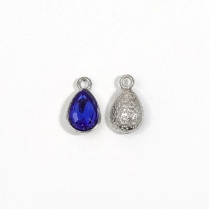 Detail of teardrop silver charm with royal blue crystal and floral engraved back