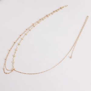 Détail d'une chaîne de corps dorée multicouche avec pendentifs papillon et étoile