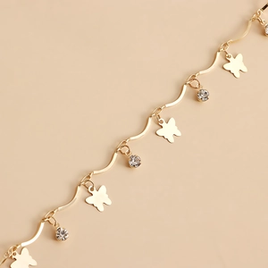 Detailed macro view of golden butterfly charms and sparkling crystals on a layered chain