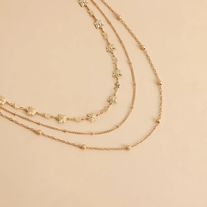 Détail de chaîne de corps dorée multicouche avec pendentifs papillon étoile et perles