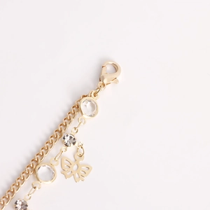 Macro shot of gold butterfly charm and crystal pendants on double-layered waist chain