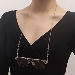 Chaîne de lunettes dorée avec breloques papillons colorées portée par un mannequin