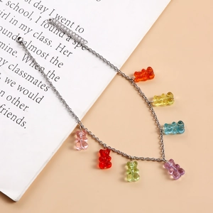 Detailed shot of silver necklace with seven colorful resin gummy bear pendants on a book