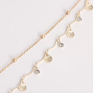 Detail showing the layered gold waist chain with shell pendant and sparkling rhinestones