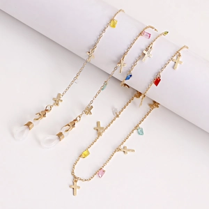 Détail de chaîne à lunettes dorée avec croix métalliques et perles colorées à facettes