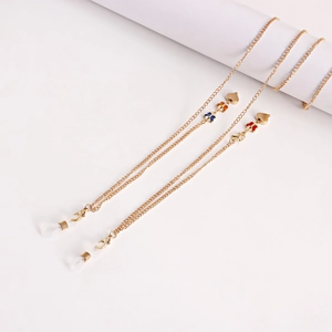 Détail de chaînes de lunettes dorées avec breloques papillons colorés et cœurs