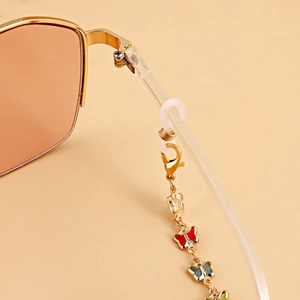 Détail d'une chaîne de lunettes dorée avec papillons colorés en émail et boucles silicone