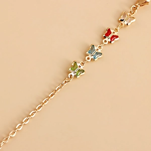 Détail d'une chaîne dorée avec quatre pendentifs papillon en émail de couleurs vives