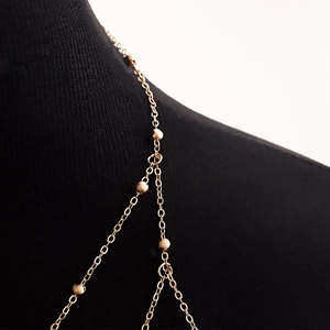 Detalle de cadena dorada para el cuerpo con cuentas en maniquí negro, estilo chic