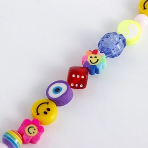 Macro shot of colorful beaded anklet with smiley faces, evil eye and sun flower charms