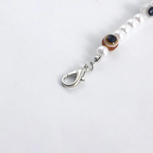Detail of beaded evil eye shoe chain with faux pearls and a silver lobster clasp