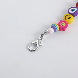 Macro shot of colorful beaded keychain with smile faces and evil eye charms on grey background