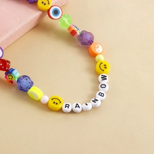 Detail of colorful beaded anklet with RAINBOW letters, smiley face and evil eye charms