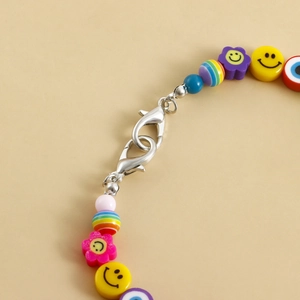 Detail of colorful beads with yellow smiley faces and evil eye charms on silver lobster clasps