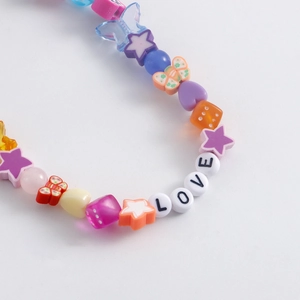 Vue macro d'une chaîne de chaussure Y2K avec perles papillon et breloques de lettres LOVE