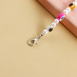 Close-up of pearl bead anklet with evil eye charms and a silver lobster clasp