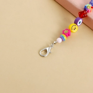 Macro detail of a vibrant beaded charm with smiley sun, evil eye, and lobster clasp