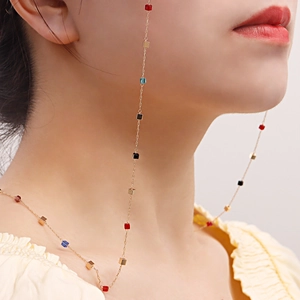 Détail d'une fine chaîne dorée ornée de micro perles cubes colorées sur un mannequin