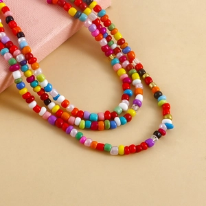 Close-up of bohemian layered multi-colored seed bead anklet on a soft pink background