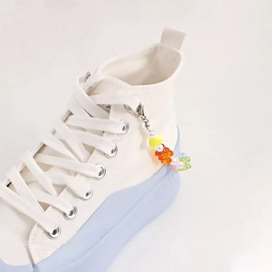 White canvas high-top sneakers with blue platform sole and colorful beaded charm chain