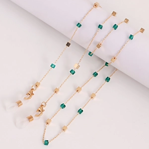 Chaîne de lunettes dorée avec cubes de cristal verts et boucles antidérapantes sur blanc