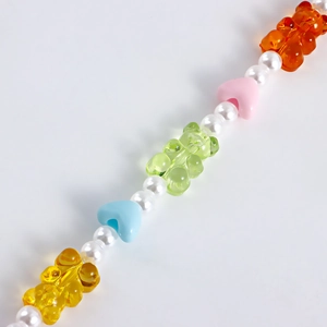 Detailed macro of colorful resin gummy bear charms and imitation pearls on a shoe chain