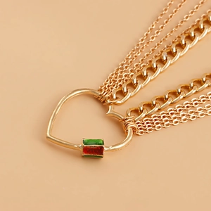 Détail d'une chaîne de taille dorée multicouche avec pendentif cœur en émail rouge et vert