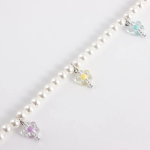 Detail of beaded shoe chain with white faux pearls and colorful transparent resin flowers