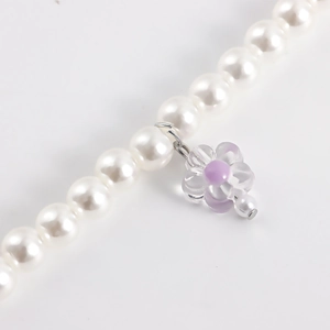 Detail of faux pearl shoe chain featuring a translucent purple flower petal charm