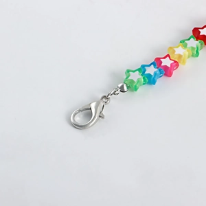 Macro shot of colorful acrylic star beads and shiny metal lobster clasp on a shoe chain