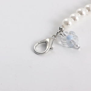 Close-up of pearl shoe chain featuring a silver lobster clasp and blue flower pendant