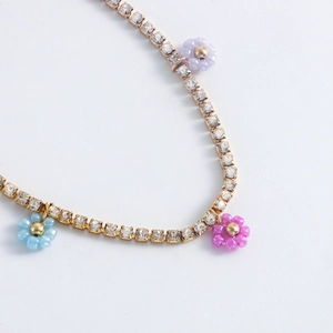 Close-up of gold chain with sparkling rhinestones and colorful beaded daisy flower pendants