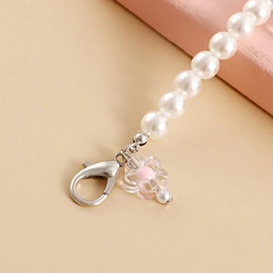 Detail of faux pearl shoe charm featuring a pink flower pendant and silver lobster clasp