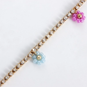 Macro detail of golden rhinestone chain with colorful beaded daisy flower charms