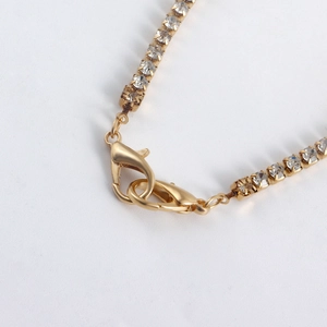 Macro view of gold-plated lobster clasp and sparkling cubic zirconia claw chain