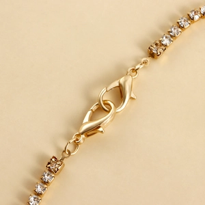 Detail of gold tennis chain anklet featuring sparkling rhinestones and double lobster clasps